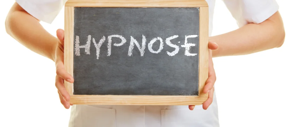 Mains qui tiennent une ardoise sur laquelle est écrit le mot "hypnose"